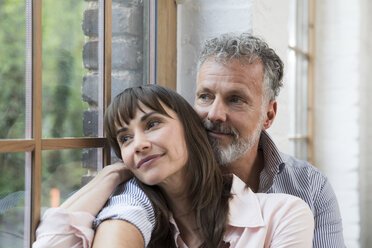 Mature couple sitting on window sill, looking out of window - FKF03080