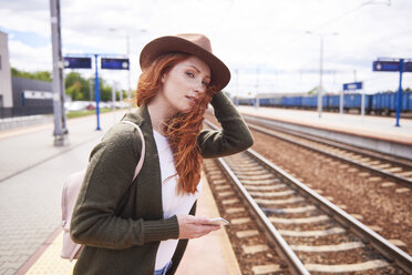 Porträt einer rothaarigen Frau mit Hut auf einem Bahnsteig - ABIF00765