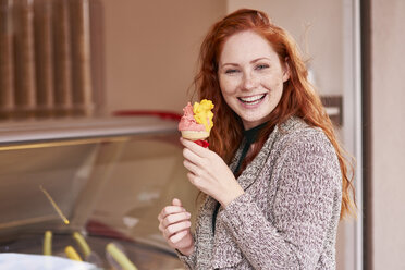 Portrait of happy redheaded woman with ice cream cone - ABIF00775