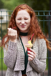 Porträt einer sommersprossigen rothaarigen Frau, die Eiscreme isst - ABIF00776