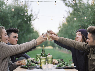 Eine Gruppe von Menschen stößt mit einem Glas Apfelwein, Speisen und Getränken auf einem Tisch an. - MINF02274