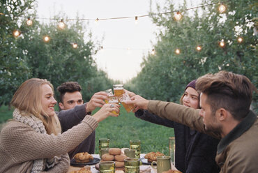 Eine Gruppe von Menschen stößt mit einem Glas Apfelwein, Speisen und Getränken auf einem Tisch an. - MINF02292