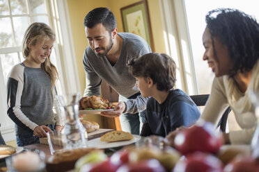 Erwachsene und Kinder versammeln sich um einen Tisch, um zu essen. - MINF02336