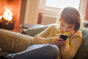 Ein junges Mädchen sitzt und schaut auf ihr Handy. - MINF02343