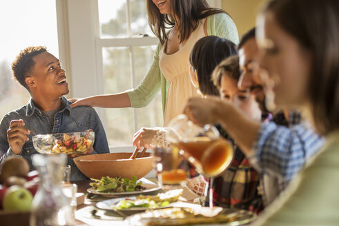 A group of people, adults and children, seated around a table for a meal. - MINF02344