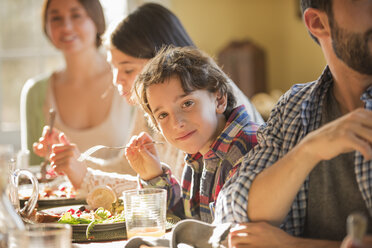 Eine Gruppe von Menschen, Erwachsene und Kinder, die sich zum Essen an einen Tisch setzen. - MINF02346