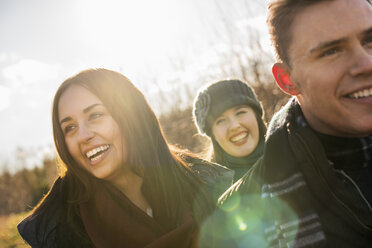 Three people, two women and a man in warm coats on a walk. - MINF02352