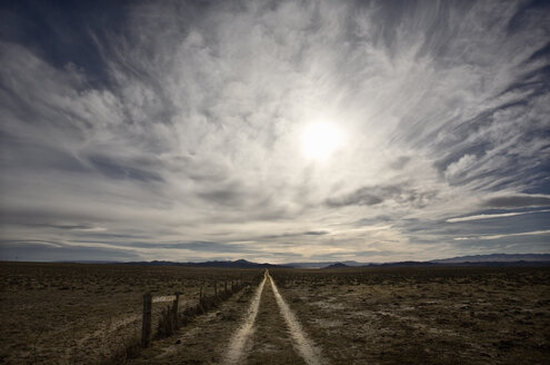 Ein großer Himmel mit Wolken über der Prärie und ein Feldweg, der in die Ferne führt. - MINF02358