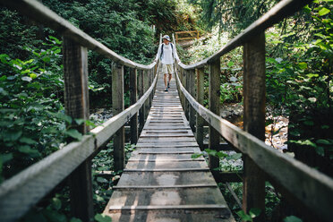 Mann geht über eine kleine Fußgängerbrücke im üppigen gemäßigten Regenwald, Oswald West SP OR - MINF02359