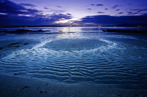 Ein Strand bei Ebbe unter einem sich verdunkelnden Himmel. Wellenmuster im Sand. - MINF02362