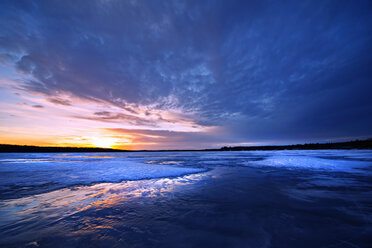 A frozen lake at dusk, and view to the setting sun on the horizon. - MINF02371