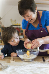 Eine Frau und ein Kind kochen an einem Küchentisch und backen Feenkuchen. - MINF02400