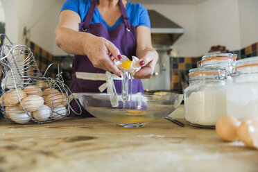 A woman at a kitchen table baking fairy cakes. - MINF02402
