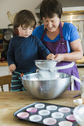 Eine Frau und ein Kind kochen an einem Küchentisch und backen Feenkuchen. - MINF02403