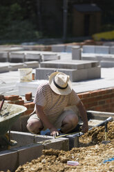 Ein Mann arbeitet auf einer Baustelle und legt das Fundament für ein Gebäude. - MINF02423