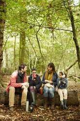 Beech woods in Autumn. Parents and two children sitting on a log having a picnic. - MINF02461