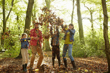 A family throwing dried leaves into the air in the woods in autumn. - MINF02467