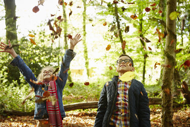 Ein Mädchen und ihr Bruder werfen Herbstblätter in die Luft. - MINF02468
