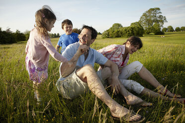 Eine Familie, zwei Eltern und zwei Kinder, an einem Sommerabend im Freien. - MINF02498