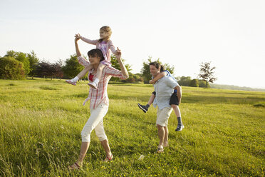 Eine Familie, zwei Elternteile, die im Sommer draußen sind und zwei Kinder huckepack nehmen. - MINF02499
