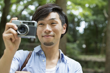 A man in a Kyoto park holding a camera, taking a picture. - MINF02509