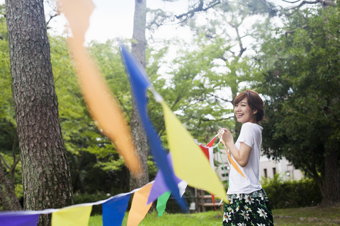 Eine Frau hält in einem Park in Kyoto eine bunte Reihe von Fahnen hoch., lizenzfreies Stockfoto