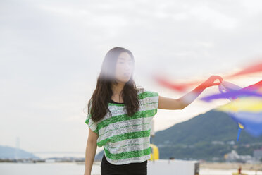 Eine Frau an einem Strand in Kobe mit Luftschlangen. - MINF02566