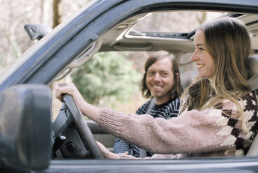 Smiling young couple driving in their car. - MINF02672