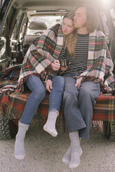 Young couple sitting in the back of their car. - MINF02676