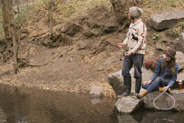 Junges Paar im Wald beim Angeln in einem Fluss. - MINF02678