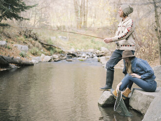 Young couple in a forest, fishing in a river. - MINF02683