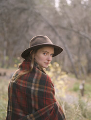 Young blond woman wearing a hat, wrapped in a blanket. - MINF02700