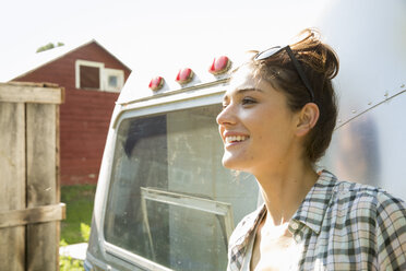 A young woman wearing sunglasses by a silver coloured trailer. - MINF02711