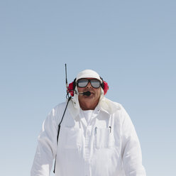 Ein Mann in weißem Overall, mit einem Funkkopfhörer, ein offizieller Zeitnehmer bei einem Autorennen, der Speed Week. - MINF02741