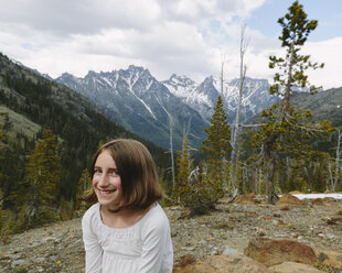Ein junges Mädchen sitzt an einem Aussichtspunkt mit Blick auf die Berge des Wenatchee National Forest. - MINF02779