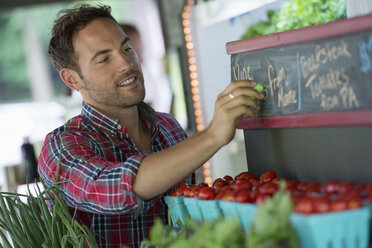 An organic fruit stand. A man chalking up prices on the blackboard. - MINF02785