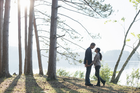 Ein Paar, das im Sommer im Schatten von Pinienbäumen spazieren geht., lizenzfreies Stockfoto