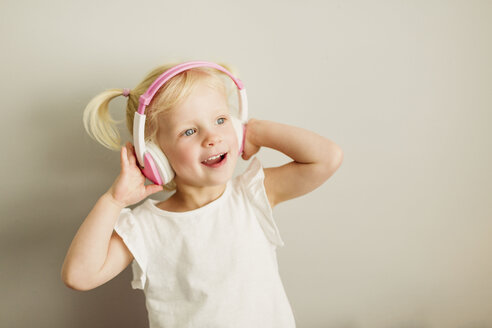 Portrait of little girl listening music with headphones dancing - NMSF00210