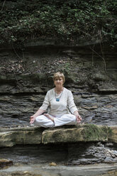 Senior woman doing yoga, meditating on rock - ALBF00582