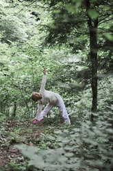 Senior woman doing yoga in the forest, triangle pose - ALBF00587