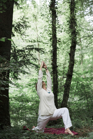 Ältere Frau beim Yoga im Wald, lizenzfreies Stockfoto