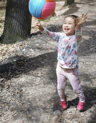 Kleines Mädchen spielt mit einem Ball in einem Park - AZF00022