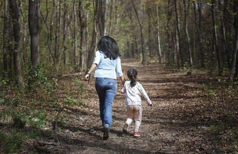 Mutter und Tochter laufen Hand in Hand in einem Park, Rückansicht, lizenzfreies Stockfoto