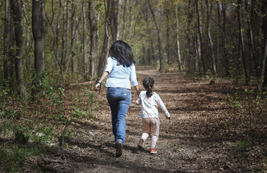 Mutter und Tochter laufen Hand in Hand in einem Park, Rückansicht - AZF00035