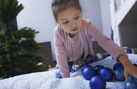 Porträt eines kleinen Mädchens mit blauen Weihnachtskugeln zu Hause, lizenzfreies Stockfoto