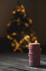Eine Rolle rot-weißes Packgarn vor einem beleuchteten Weihnachtsbaum - AZF00046