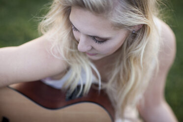 Frau spielt Gitarre im Gras - ISF17213