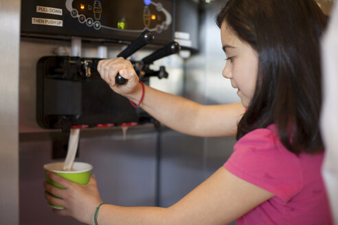Mädchen gießt Becher mit gefrorenem Joghurt ein - ISF17219