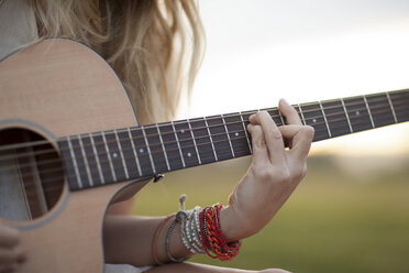 Frau spielt Gitarre im Gras - ISF17231