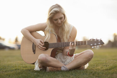 Frau spielt Gitarre im Gras - ISF17232